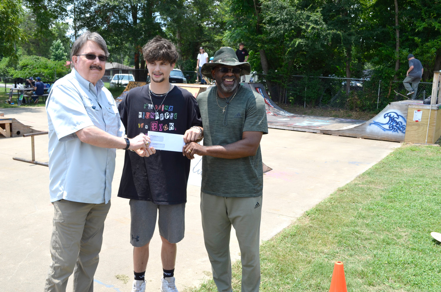 Roy Shockey, left, president of the Mineola Kiwanis Club, presents a check for $500 to Nathan Witt with the Flint and Steel Coalition, center, and Demethrius Boyd, pastor of St. Paul Missionary Baptist Church for use to improve the St. Paul Community Skate park during last week’s skate day competition.
